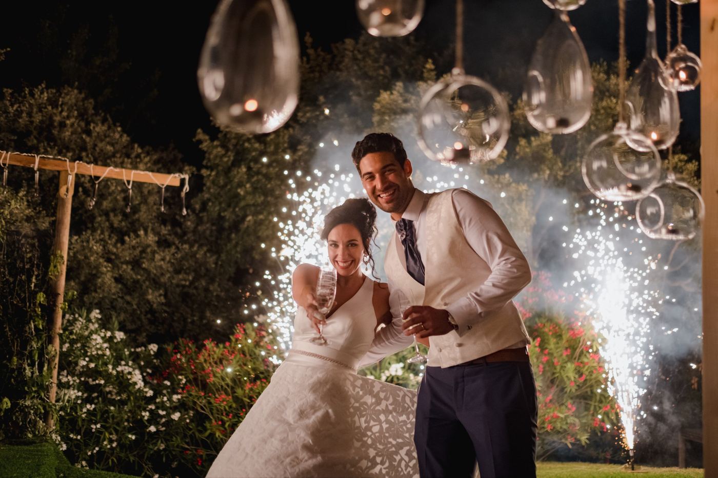 Noivos a brindar com fontes de luz no jardim