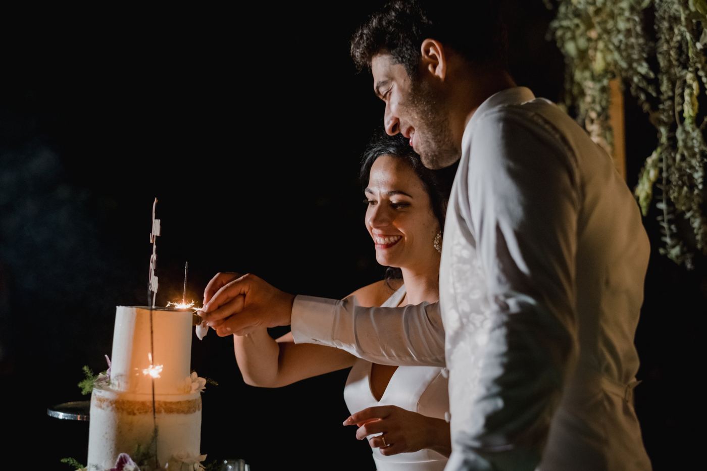 Noivos a cortar o bolo com velas faísca